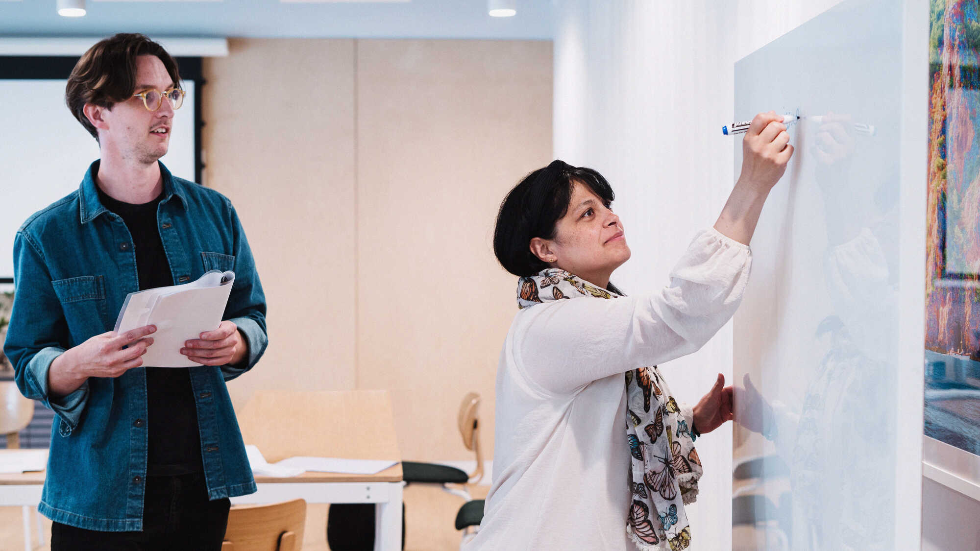 a photo of two Flatiron UK employees brainstorming at a whiteboard