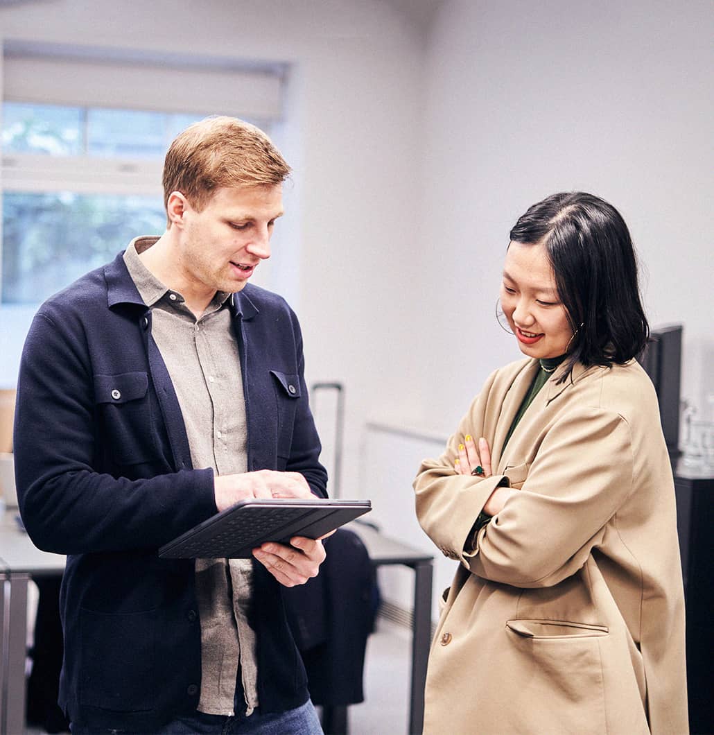 a photo of two Flatiron UK employees having a conversation while looking at a tablet screen